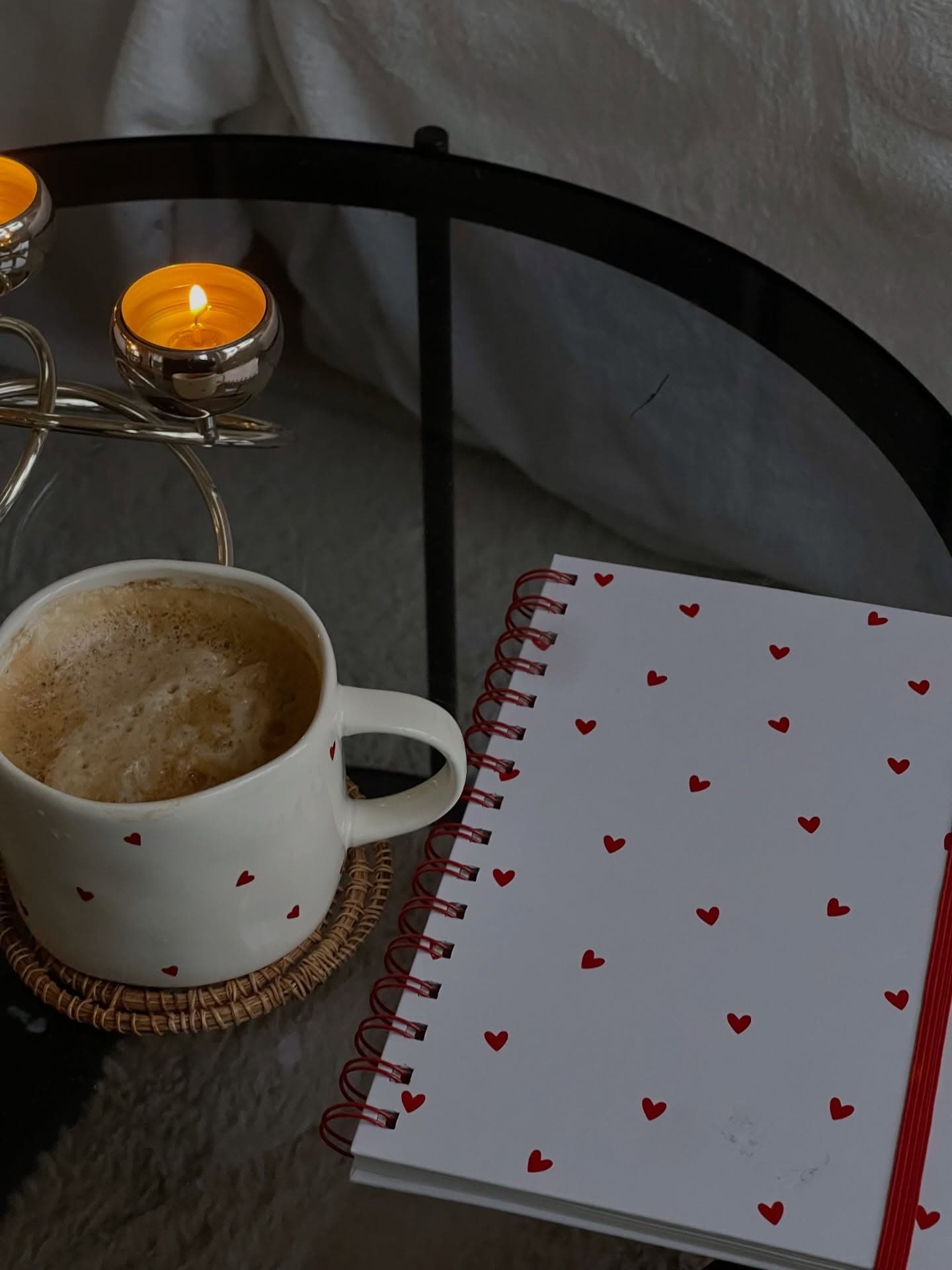 Candle, latte and heart-print notebook on a rest day